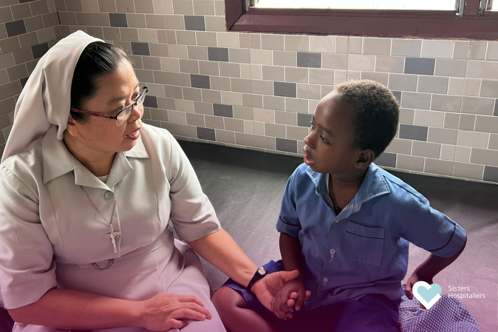 Sister Hospitaller listening and speaking with a child in a moment of compassionate care