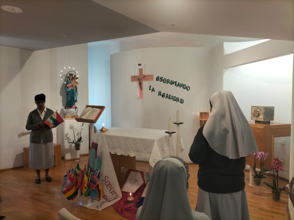 Sisters praying with national flags representing the global presence of the Congregation