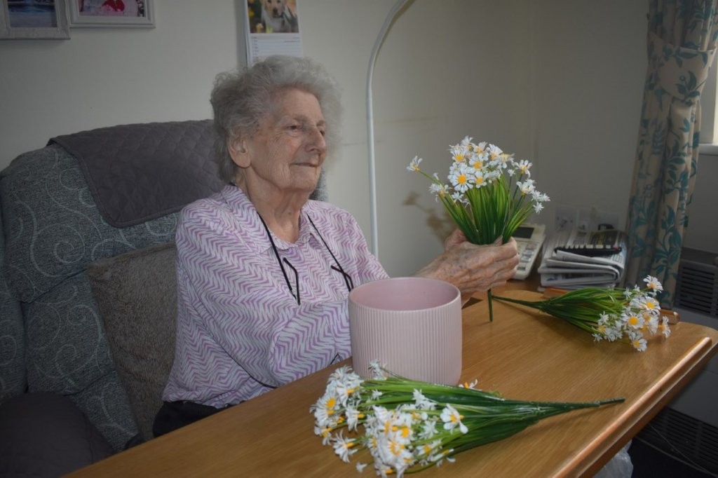 Resident arranging flowers during a creative activity at Footherley Hall